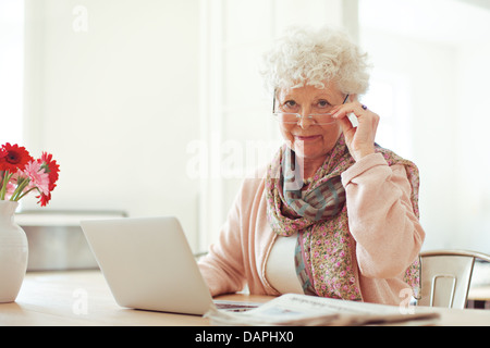 Hauts élégant woman at home with laptop looking at you Banque D'Images