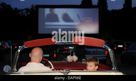 Un père et son fils s'asseoir dans leur décapotable de regarder un film dans un cinéma drive-in temporaire sur un parking en face de la foire de Hanovre (Allemagne), 2 septembre 2011. Le son du film est directement transmise par des fréquences radio pour la radio de la voiture. Photo : Julian Stratenschulte Banque D'Images