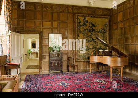 Salon avec lambris de chêne jacobéen tapisserie flamande et grand piano in Ampney Park, maison de campagne Anglaise du 17e siècle Banque D'Images