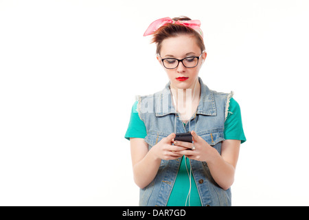 Adolescente, habillé de façon décontractée, pose maintenant un iphone d'écouter de la musique, de parler au téléphone et prendre des photos d'elle-même. Banque D'Images