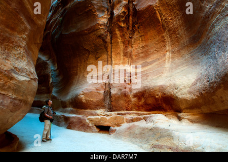 Randonneur admirant les imposantes falaises de grès dans le Siq, Petra, Jordanie Banque D'Images