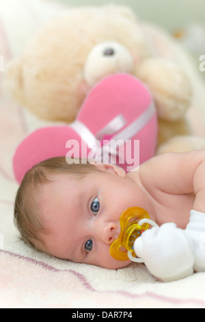 Infant baby (1 mois) lying on bed with teddy bear Banque D'Images