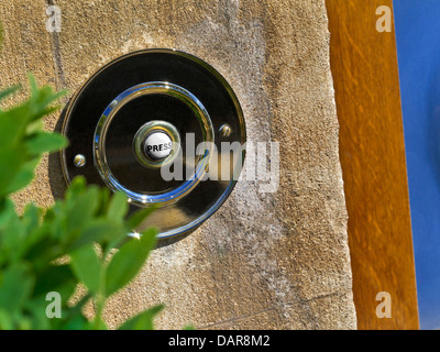 Cloche de porte traditionnelle laiton avec «presse» en métal ensoleillé sur vieux Cotswolds Cottage mur en pierre Royaume-Uni Banque D'Images