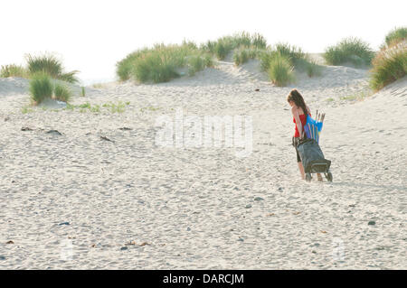 L'estuaire de Dovey/Borth, Ceredigion, pays de Galles, Royaume-Uni. 17 juillet 2013. Une jeune femme arrive avec son buggy. Une étendue de sable plat dur - qui offre un immense parking pour les voitures à 1 € par voiture par jour - dans la Dovey Dyfi (en gallois) Estuaire, fait partie d'une grande surface des eaux côtières soutenue par la campagne du Pays de Galles et du Conseil ainsi que les dunes de sable environnantes offre un magnifique salon pour les gens d'échapper à la vague de chaleur qui a été la Grande-Bretagne torride pendant près de deux semaines. L'accueil cool brise de mer soufflent en provenance de la mer d'Irlande. Crédit photo : Graham M. Lawrence/Alamy Live News. Banque D'Images