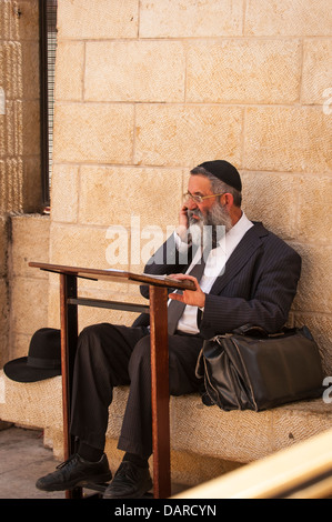 Vieille ville de Jérusalem Israël du mur des Lamentations Ha Kotel Plaza juif orthodoxe priant homme s'arrête de parler sur mobile cell phone Banque D'Images