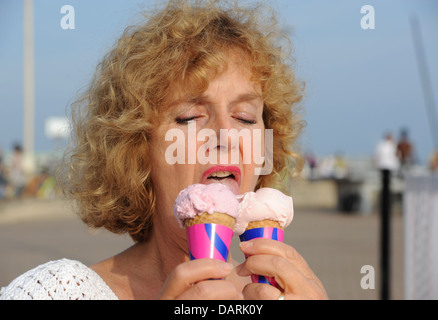 Mature femme d'âge moyen 50 ans eating ice cream cones par temps chaud Banque D'Images