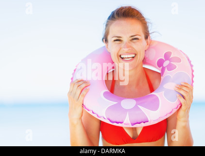 Portrait of smiling young woman on beach avec anneau de bain Banque D'Images