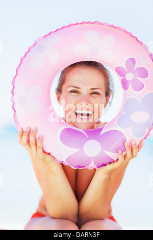 Portrait of smiling young woman on beach avec anneau de bain Banque D'Images