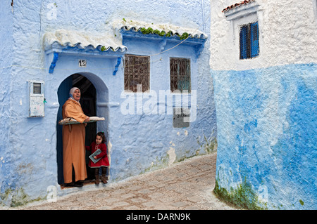 Femme et sa fille à propos d'apporter du pain pour le four dans la médina de Chefchaouen bleu. Région du Rif, au Maroc Banque D'Images