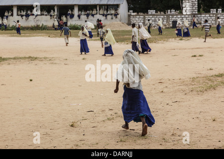 L'Afrique, Tanzanie, Zanzibar, l'île de Pemba. Les écoliers en marche pour regarder la tauromachie tanzanien traditionnel. Banque D'Images