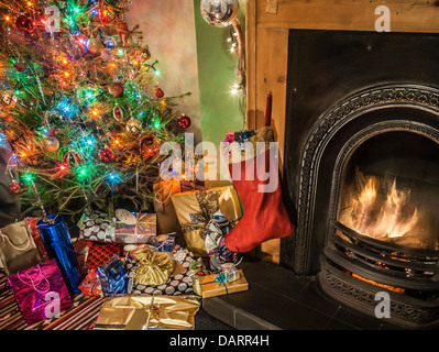 Une agréable cheminée avec arbre de Noël, décorations, l'ensemencement et présente. Banque D'Images