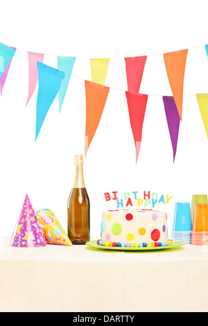 Bouteille de vin mousseux, verres en plastique, chapeaux de fête et anniversaire gâteau sur une table Banque D'Images
