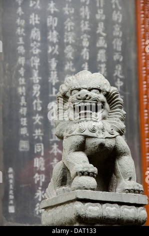 La Chine, Shanghai, Temple du Bouddha de Jade. Statue de lion en pierre en face de signer avec des symboles chinois. Banque D'Images