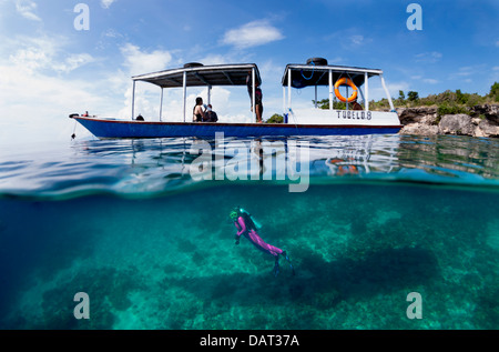 Duplex vue de blonde diver reef explorer ci-dessous bateau de plongée à côté de l'île tropicale Banque D'Images