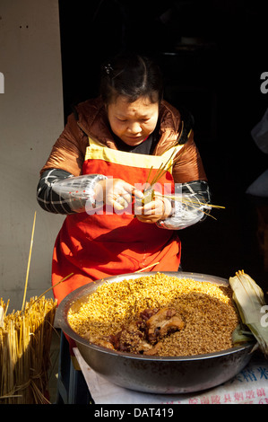 La Chine, périphérie de Shanghai. Zhujiajiao. Woman making local snack populaire de porc et de riz gluant enveloppé dans des feuilles. Banque D'Images