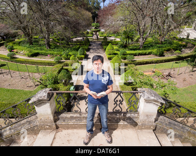 Portrait d'homme tenant un livre dans un parc looking at camera Banque D'Images