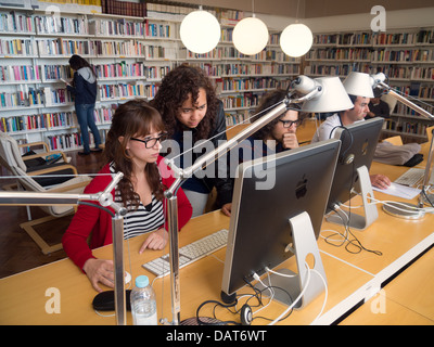 Deux femmes à l'aide d'un ordinateur Apple iMac in library Banque D'Images