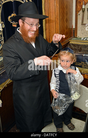 Un enfant de 3 ans garçon juif religieux obtenir sa première coupe de cheveux - Une serrure couper ici par son père - à un rituel appelé une Upsherinish. Banque D'Images