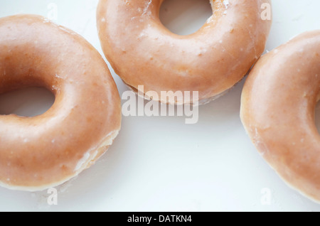 Beignets chauds fraîchement préparés avec du glaçage et au bord de l'armature, de près. Banque D'Images