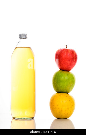 Le jus de pomme en bouteille en verre et trois pommes mûres Banque D'Images