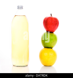 Le jus de pomme dans une bouteille en verre et trois pommes mûres Banque D'Images