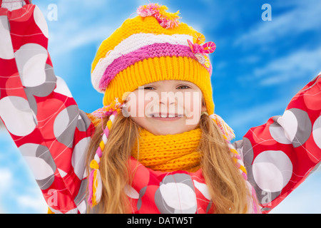 Close-up portrait of happy young girl à 5 ans vêtements rouge vif avec les mains levées debout dans la neige Banque D'Images