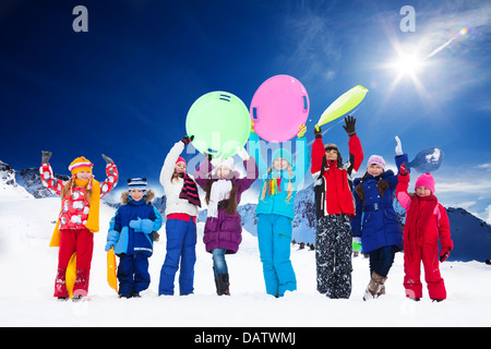 Rangée de grand groupe d'enfants, amis, garçons et filles, se tenant ensemble dehors dans la neige, lever les mains, de nombreux holding Sled Banque D'Images