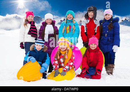Groupe d'heureux garçons et filles, chacun tenant un traîneau, debout ensemble dans la neige Banque D'Images