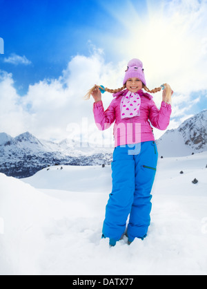 Close up portrait of cute smiling Caucasian girl in pink coat standing in snow Banque D'Images