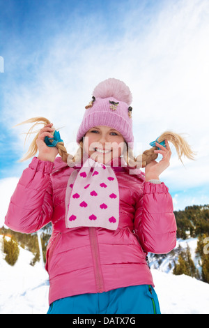 Portrait of cute smiling blonde woman in pink coat debout dans la neige Banque D'Images