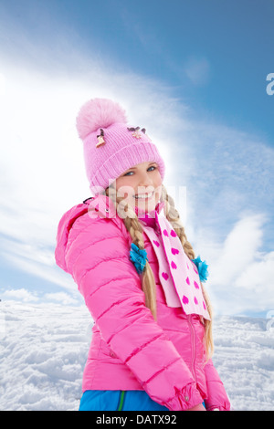 Portrait of cute smiling blonde woman in pink coat debout dans la neige Banque D'Images