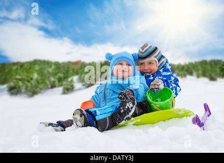 Deux petits garçons frères assis sur la neige et jouer ensemble sur la journée d'hiver Banque D'Images