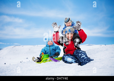 Trois frères assis sur la neige et jouer ensemble sur la journée d'hiver Banque D'Images