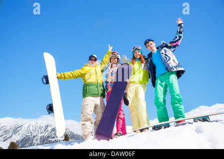 Heureux les hommes et les femmes d'amis stand dans la neige avec les planches du levage et des signes avec la main Banque D'Images