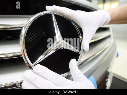 Un employé du constructeur automobile DaimlerChrysler AG portant des gants de coton blanc fixe la célèbre étoile à trois branches avec un joint torique neuf Mercedes Benz logo sur la calandre d'une Mercedes Benz Classe S Berline à l'usine de Sindelfingen, Allemagne, vendredi, 02 février 2007. DaimlerChrysler emploie 29 900 personnes dans ses plus grandes installations de production dans le monde entier à Sindelfingen, qui da Banque D'Images