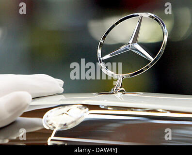 Un employé du constructeur automobile DaimlerChrysler AG portant des gants de coton blanc fixe la célèbre étoile à trois branches avec un anneau simple logo Mercedes Benz sur le capot moteur d'une Mercedes Benz Classe S Berline à l'usine de Sindelfingen, Allemagne, vendredi, 02 février 2007. DaimlerChrysler emploie 29 900 personnes dans ses plus grandes installations de production dans le monde entier à Sindelfingen, dai Banque D'Images