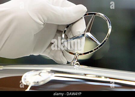 Un employé du constructeur automobile DaimlerChrysler AG portant des gants de coton blanc fixe la célèbre étoile à trois branches avec un anneau simple logo Mercedes Benz sur le capot moteur d'une Mercedes Benz Classe S Berline à l'usine de Sindelfingen, Allemagne, vendredi, 02 février 2007. DaimlerChrysler emploie 29 900 personnes dans ses plus grandes installations de production dans le monde entier à Sindelfingen, dai Banque D'Images