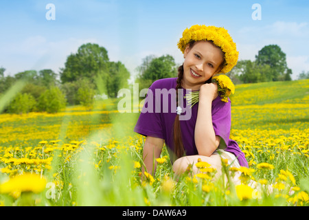 Belle 10 ans brunet fille assise dans le parc et un bouquet de pissenlits avec grand sourire Banque D'Images