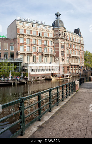 Le NH Doelen Hotel par la rivière Amstel, dans la ville d'Amsterdam, Pays-Bas. Banque D'Images