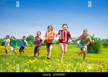 Groupe de sept professionnels courir dans le parc les enfants, garçons et filles, de race blanche et noire Banque D'Images