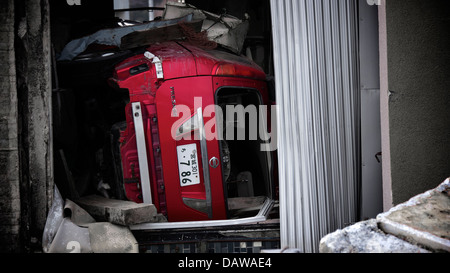 Une Nissan Prestige coincé sous les débris dans l'un des bâtiment renversé au quartier gravement endommagé Onagawa Banque D'Images