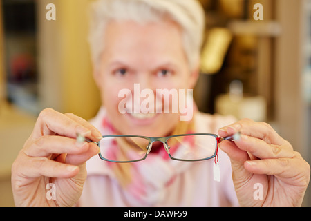 Smiling senior opticien holding nouvelles lunettes dans ses mains Banque D'Images