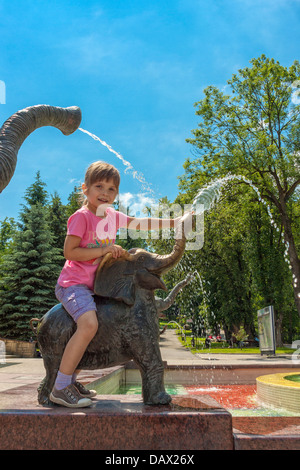 Fille assise sur une fontaine de l'éléphant à Rabka-Zdrój, Pologne Banque D'Images