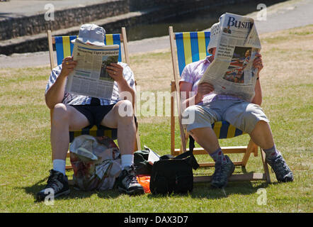 Bournemouth, Royaume-Uni 19 Juillet 2013. Continue comme tête sunseekers canicule à Bournemouth. Couple de personnes âgées assis dans des chaises longues de lire les journaux porter un chapeau pour protéger la tête du soleil à Jardins de Bournemouth. Credit : Carolyn Jenkins/Alamy Live News Banque D'Images