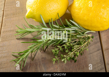 Citrons frais avec le romarin et le thym sur une table en bois Banque D'Images