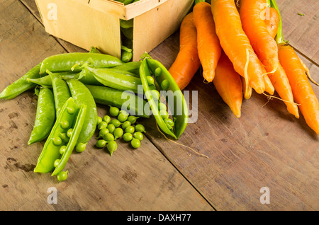 Pois verts écossés fraîchement récoltées et les carottes