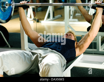 Man lifting un barbell dans une salle de sport faire des exercices de musculation Banque D'Images