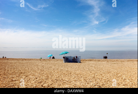 Vue de personnes, un brise-vent, et parasols, sur la plage de King's Lynn, Norfolk, Angleterre, Royaume-Uni. Banque D'Images