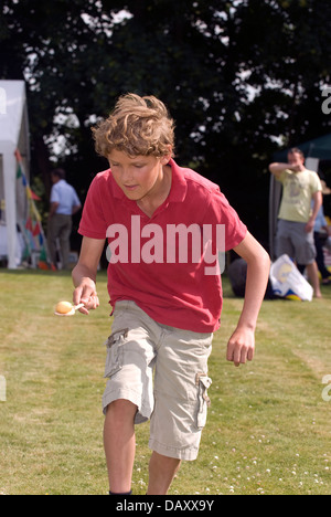 Jeune garçon prenant part à la course à l'oeuf et la cuillère worldham fête du village, Hampshire, Royaume-Uni. dimanche 14 juillet 2013. Banque D'Images