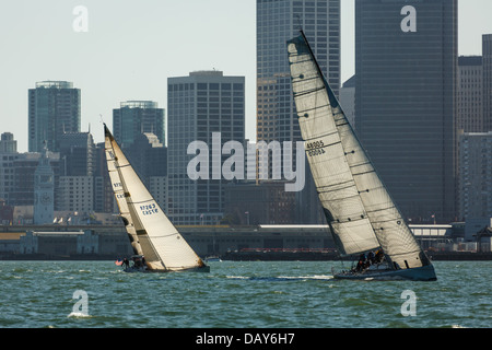 Deux courses de voiliers côte à côte dans la baie de San Francisco, en face de la hauteur des bâtiments de la ville sur une journée ensoleillée Banque D'Images